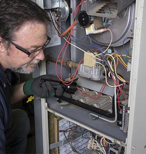 Technician inspecting water heater components with flashlight, highlighting appliance repair services offered by Carter Services.