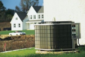 Air conditioning unit on lawn beside residential home, emphasizing importance of HVAC maintenance for home comfort during summer months.