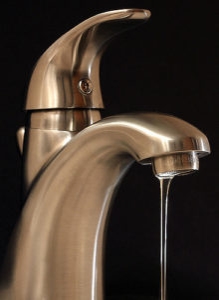 Stainless steel faucet with water flowing, highlighting Carter Services' commitment to plumbing and water quality.