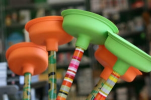 Colorful plungers in a store display, featuring bright orange and green colors, for plumbing solutions by Carter Services.